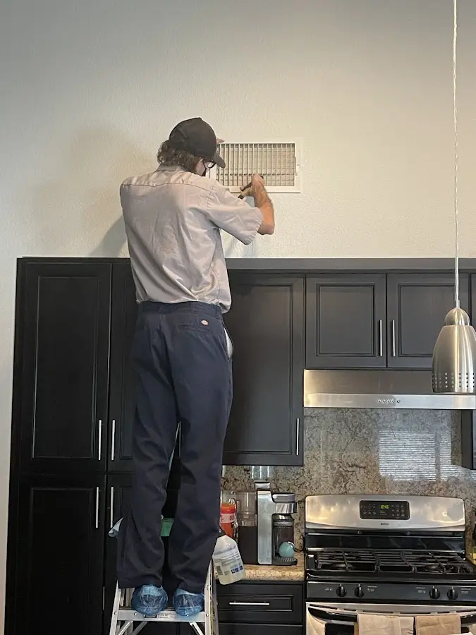 Technician inspecting an air vent during HVAC service in Haines City